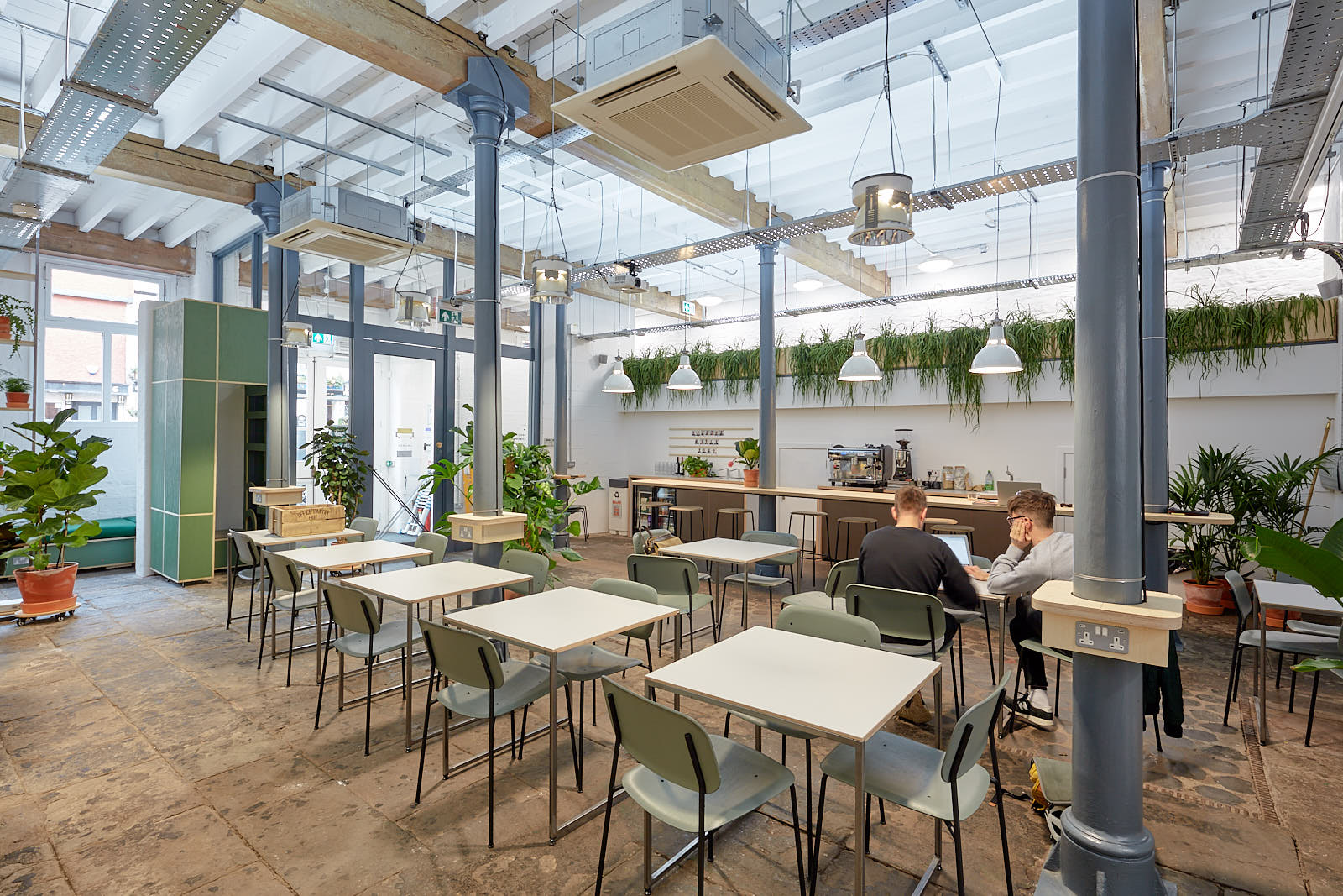 The glazed winter garden workspace with cafe tables and planting