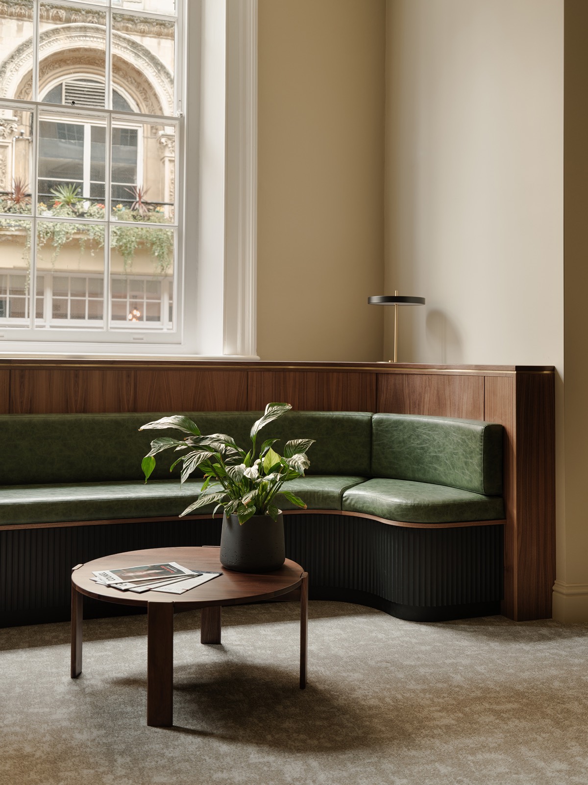 The reception lounge with green banquette seating and walnut panelling
