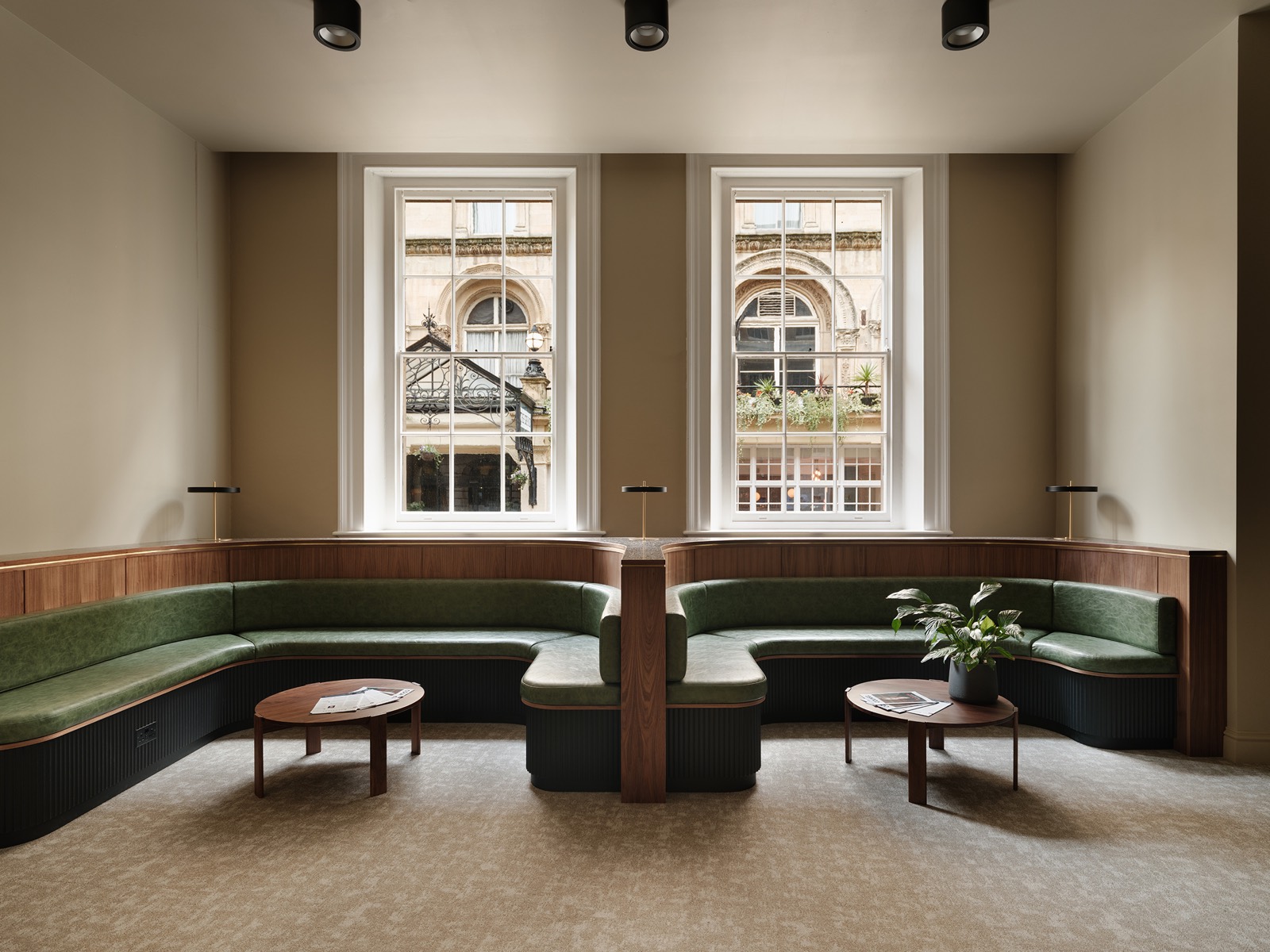 A panelled meeting room with banquette seating at the windows