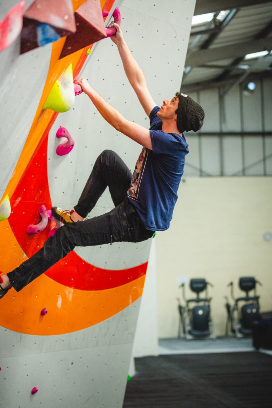 A climber on the orange and white bouldering wall
