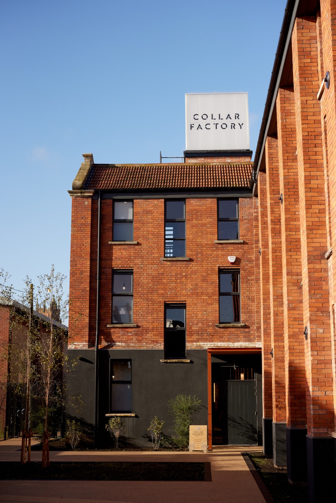 The brick front of the factory with its dark metal extension