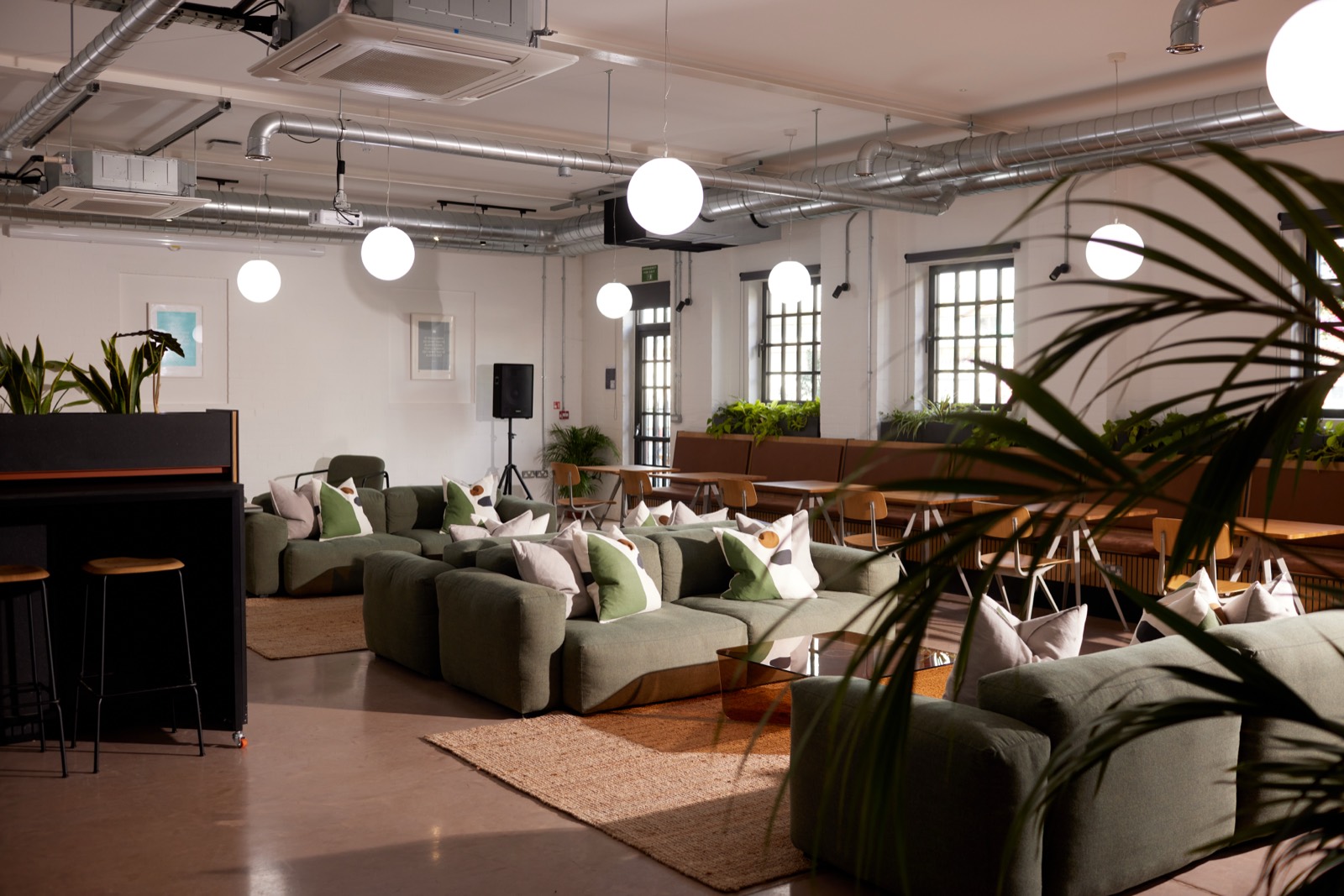 The main co working hall with green seating under white roof trusses