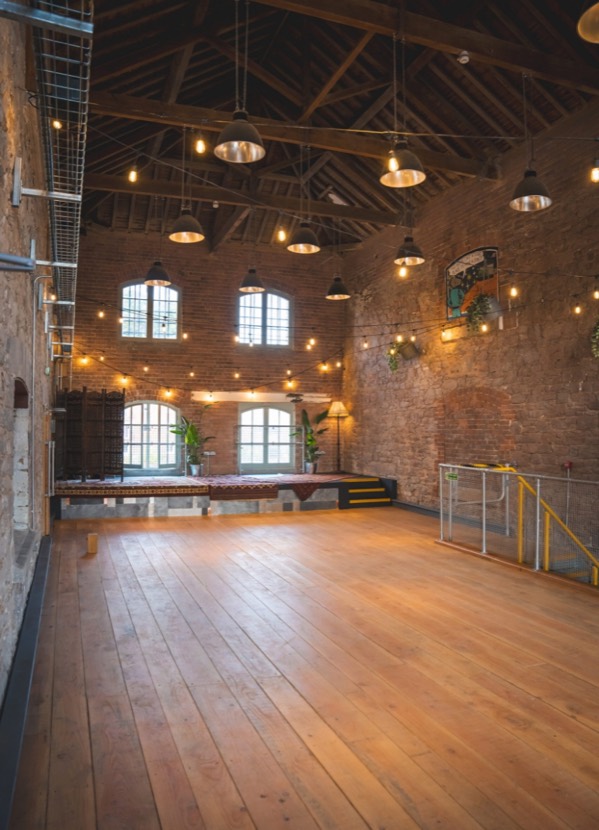The taproom hall as found, stone walls and timber floor under festoon lighting
